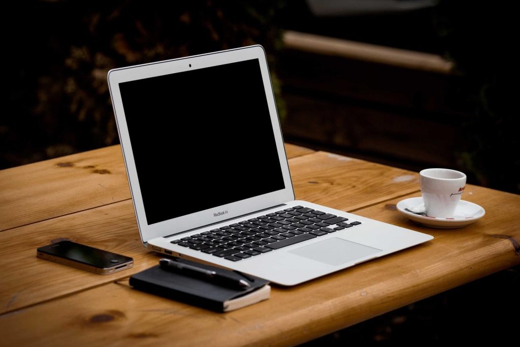 Ordinateur portable, téléphone et tasse de café sur une table en bois